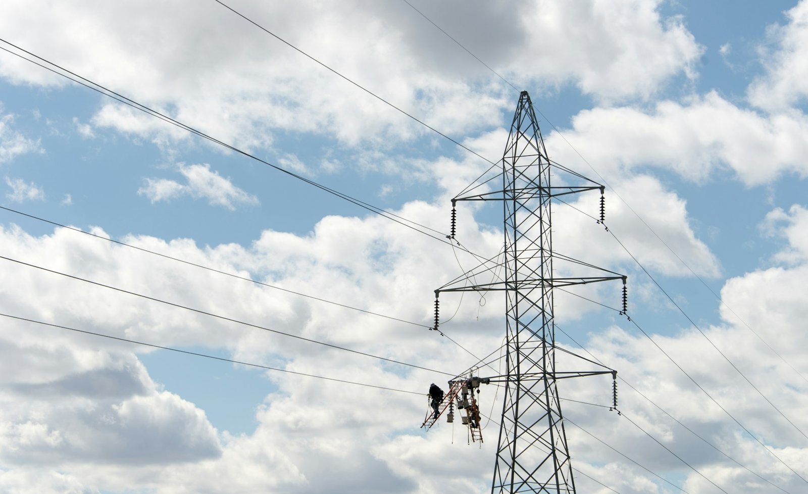 Transmission tower and power lines with a maintenance crew working from an elevated platform